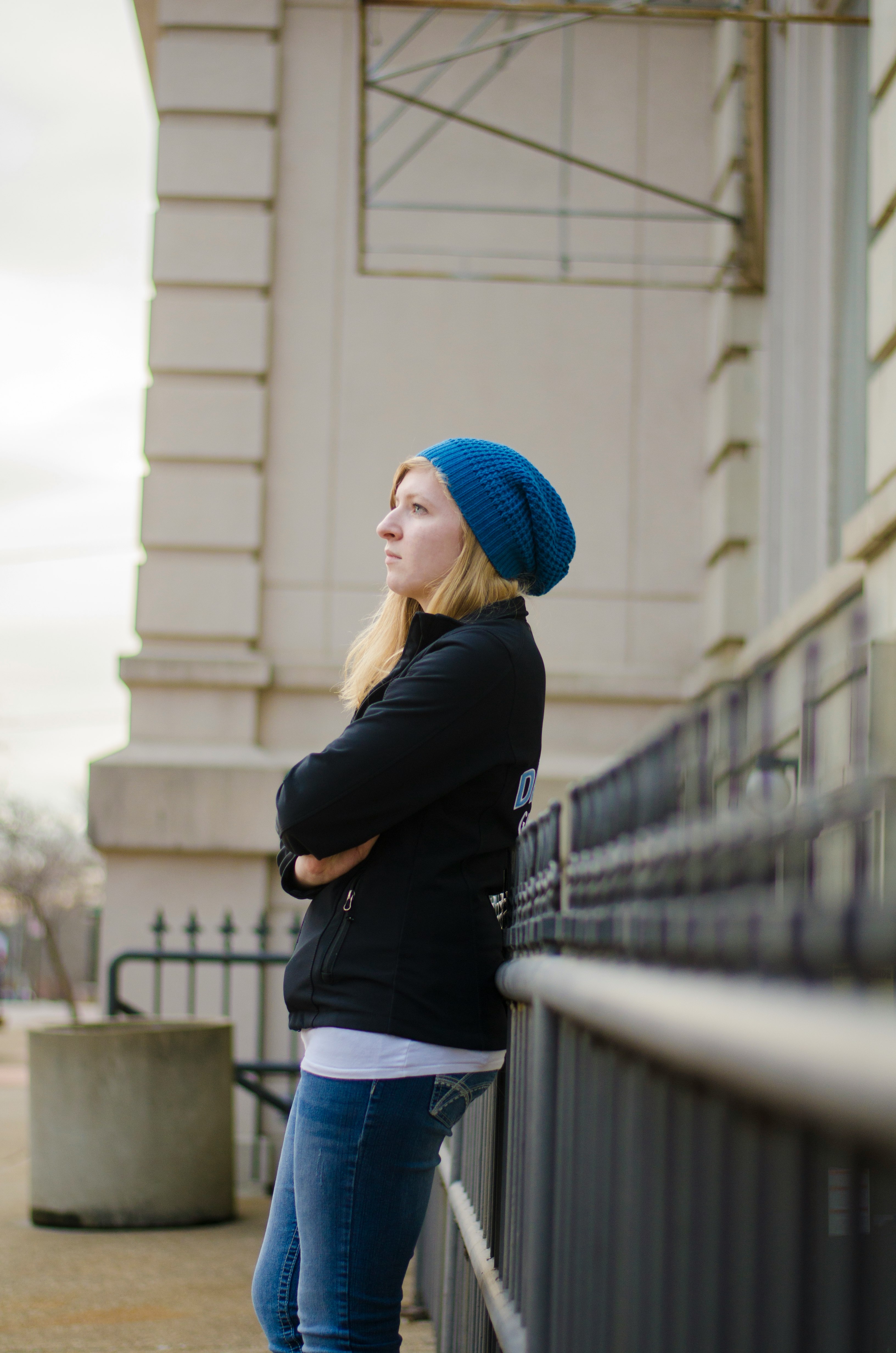 woman in blue knit cap and black long sleeve shirt standing on bridge during daytime